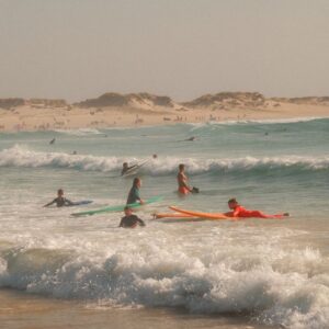A vibrant scene of surfers and waves enjoying a sunny beach day.